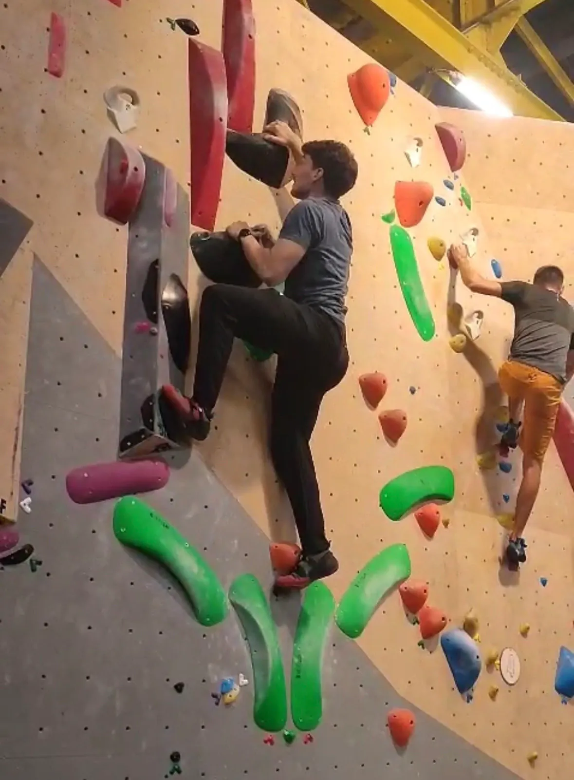 Two AEGEE Toulouse members on a bouldering wall, one reaching for a hold