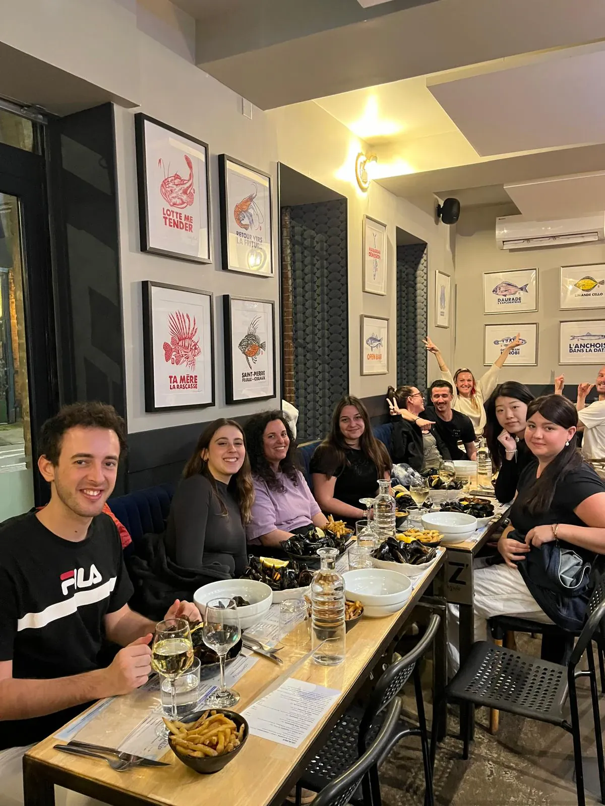 A group at a seafood restaurant table with bowls of mussels and fries