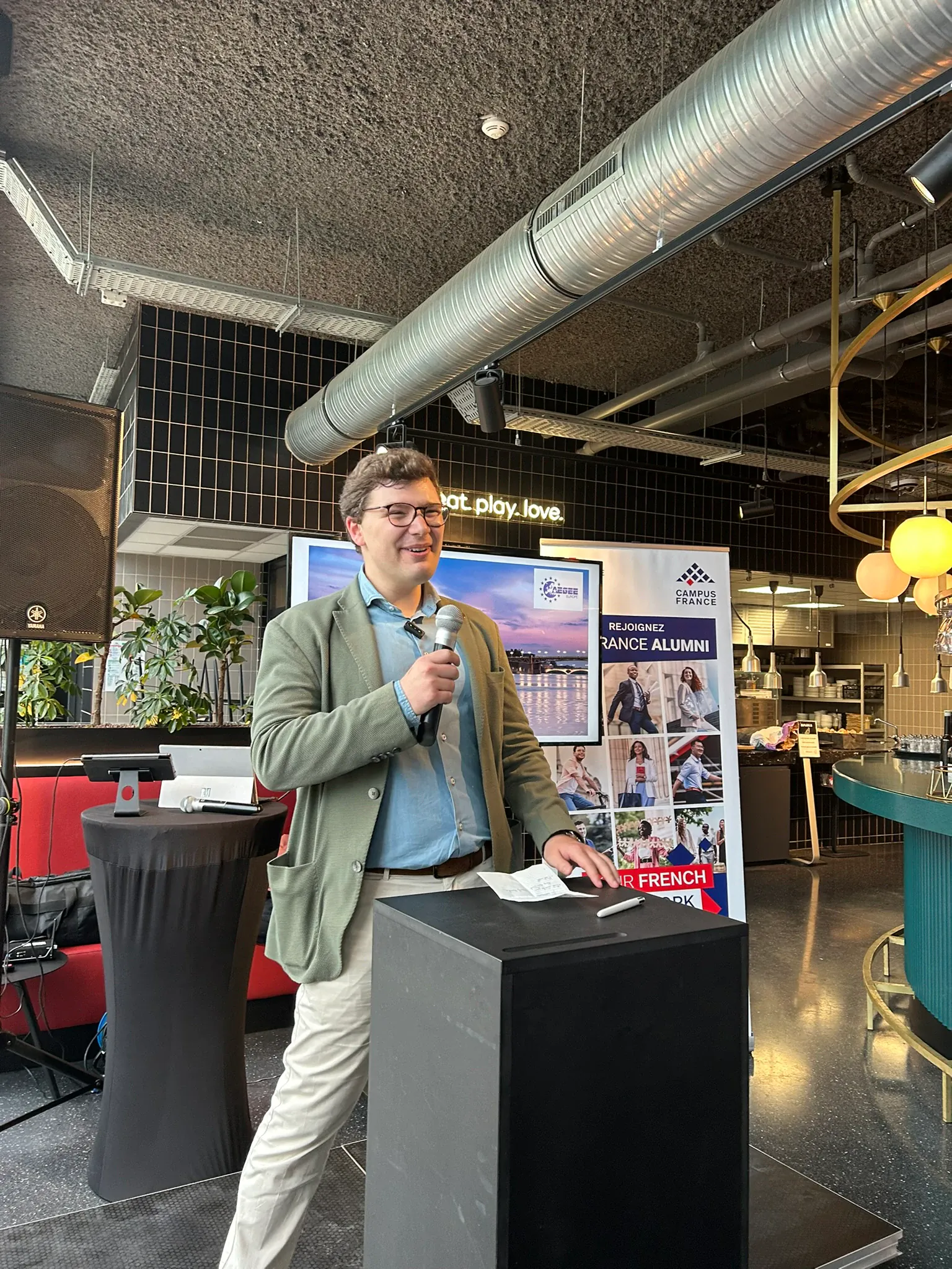 A speaker addressing a room with a microphone at a farewell event