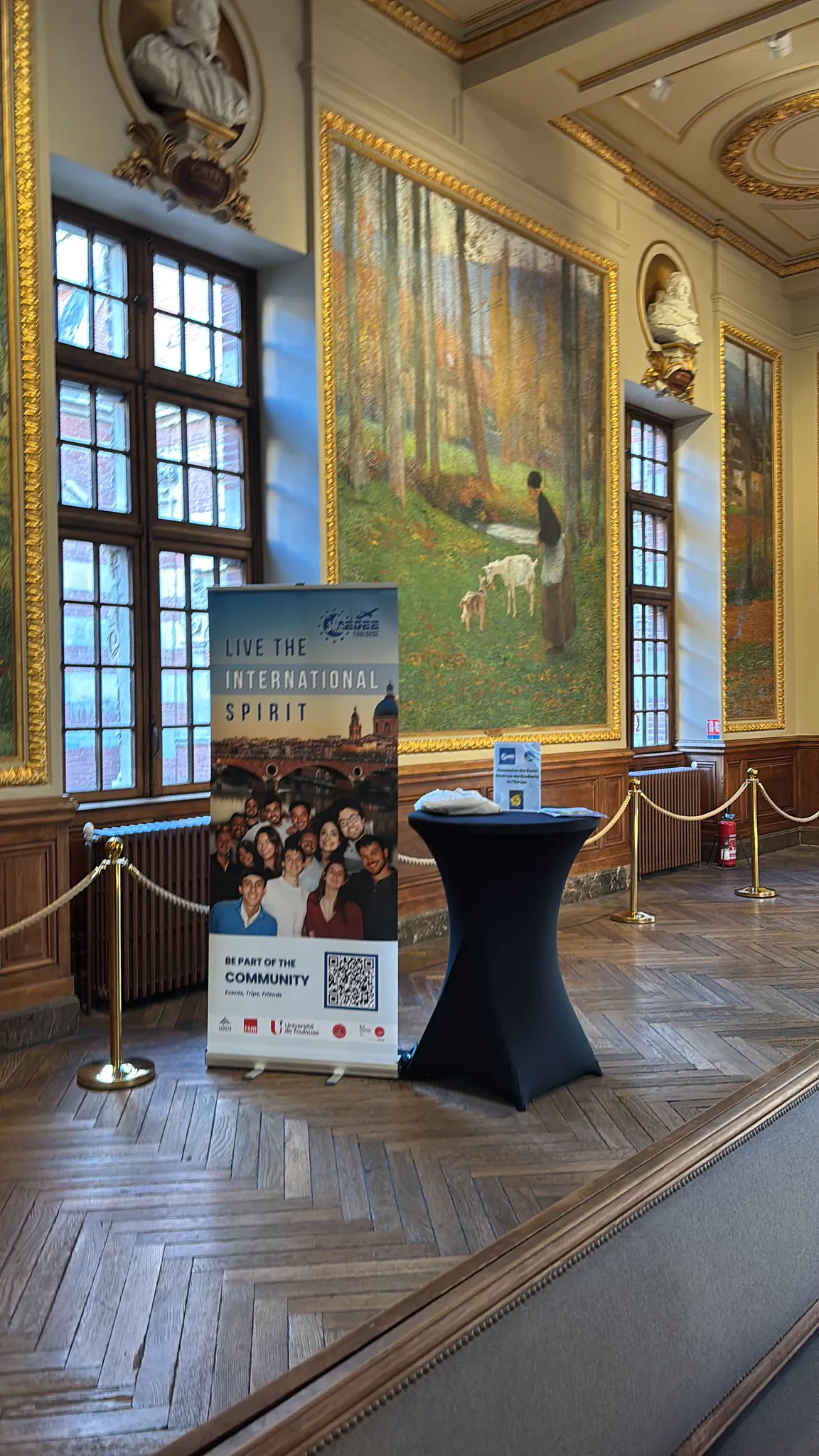 An information banner and table set up in a grand, ornately decorated hall