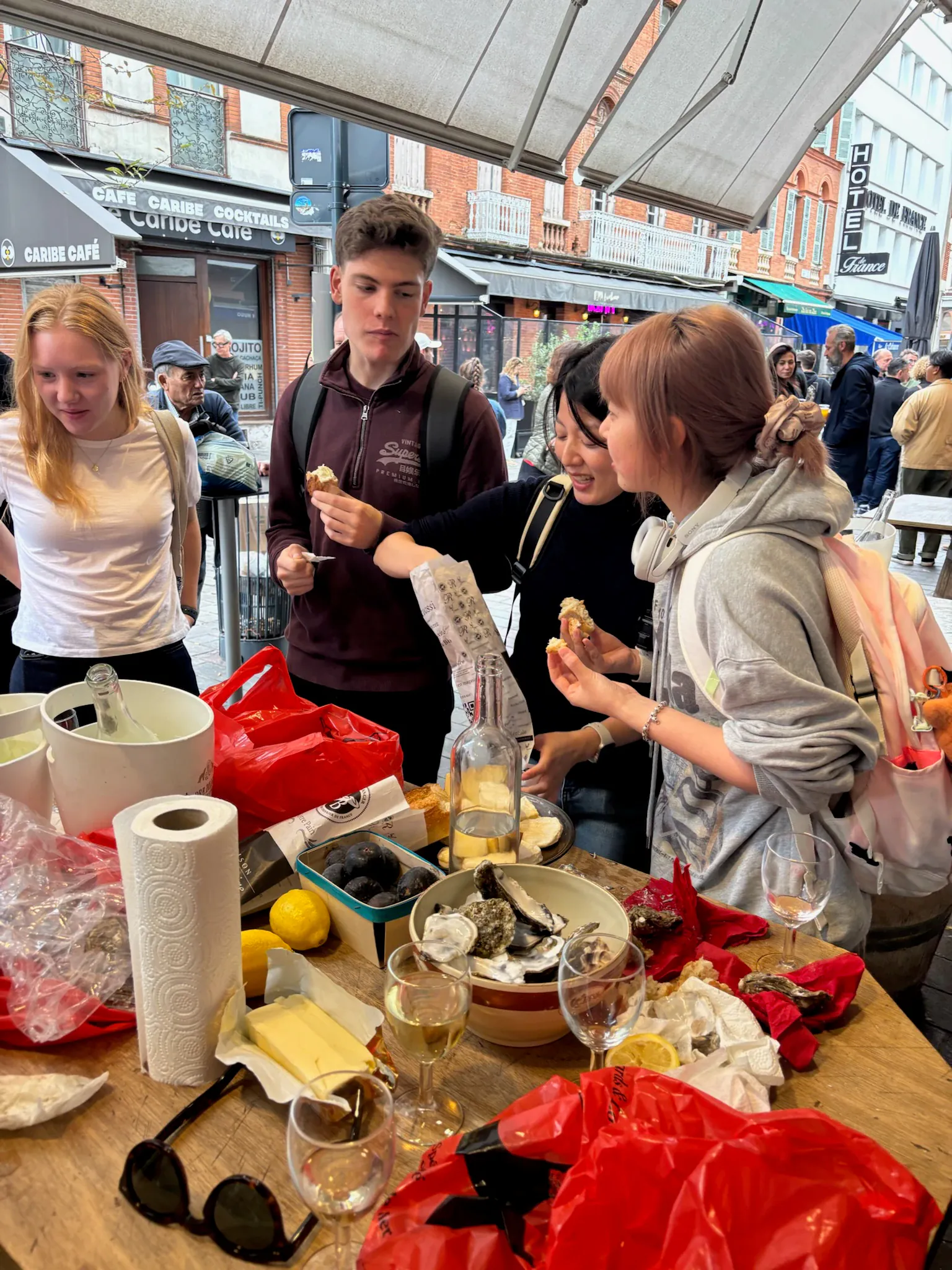 A group tasting oysters and bread at an outdoor market stall