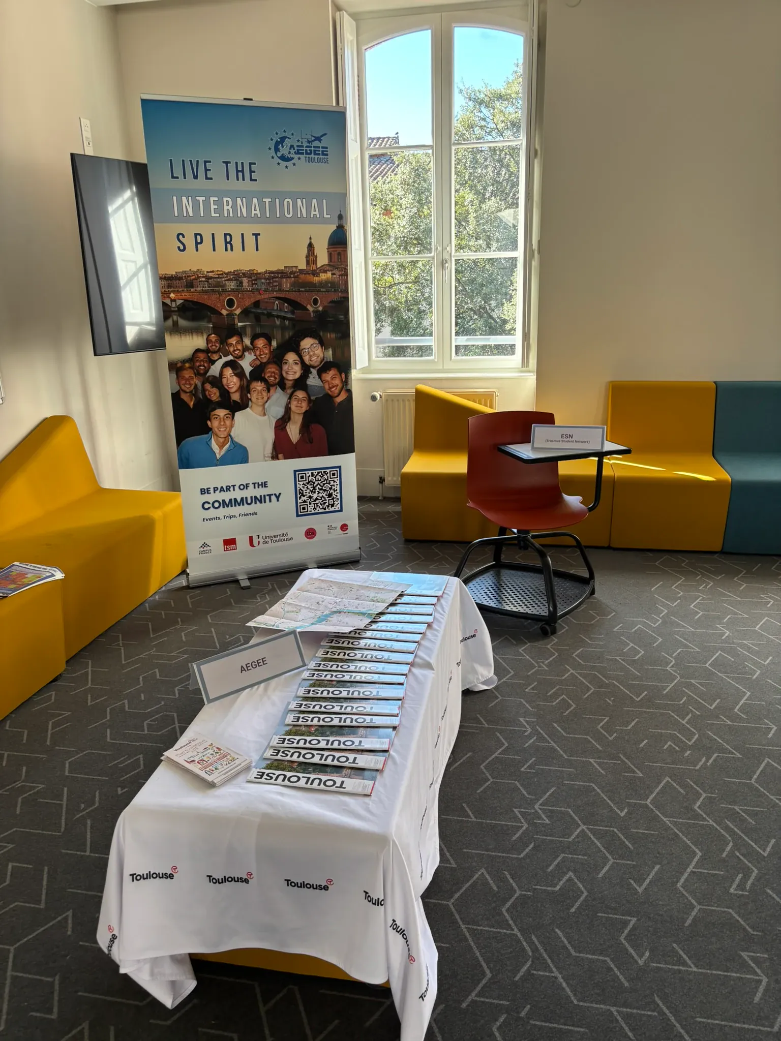 An information banner and table set up in a bright lounge space with a reserved seat for a partner association
