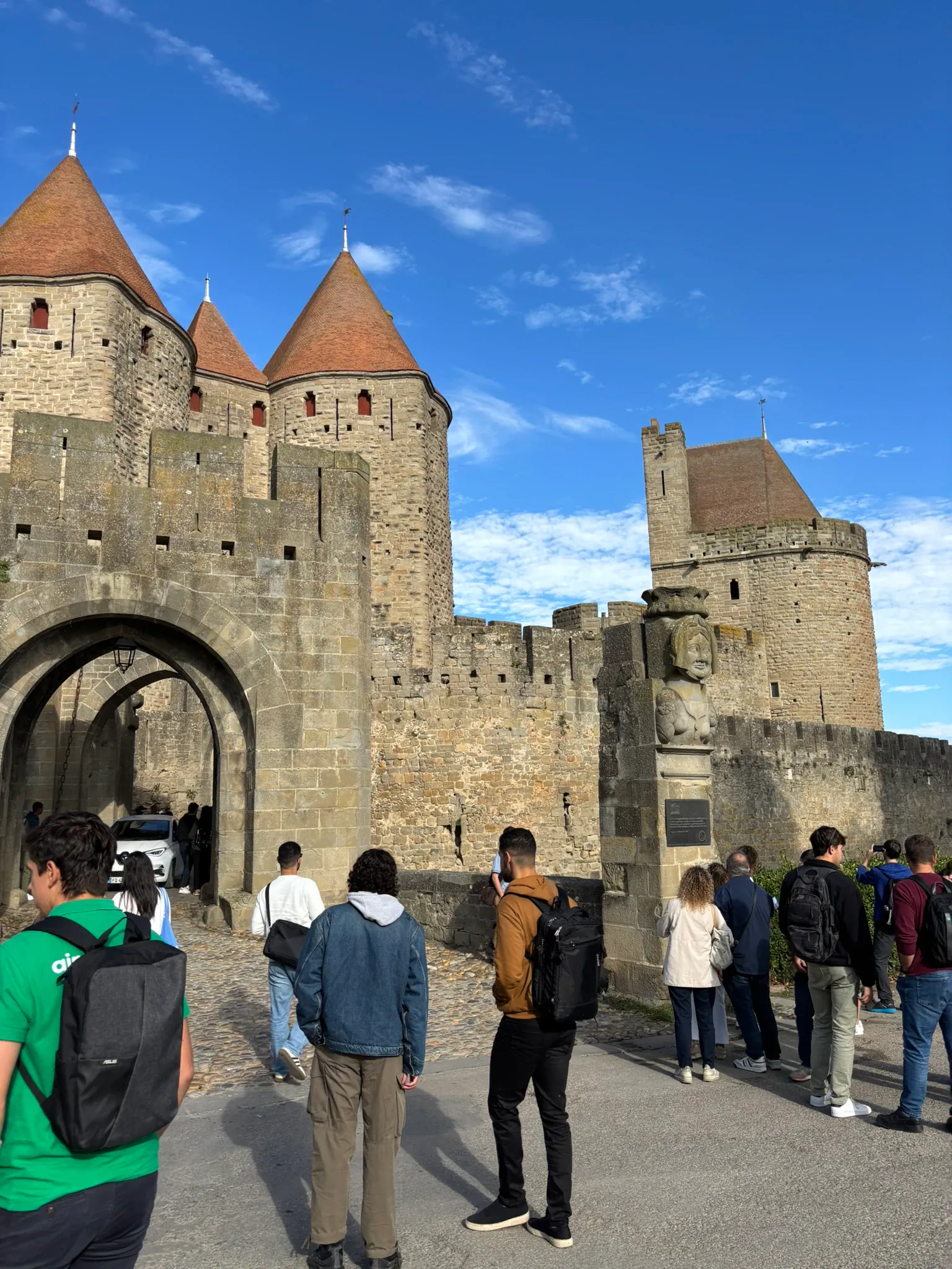 A group facing the fortified stone gates and towers of a medieval walled city