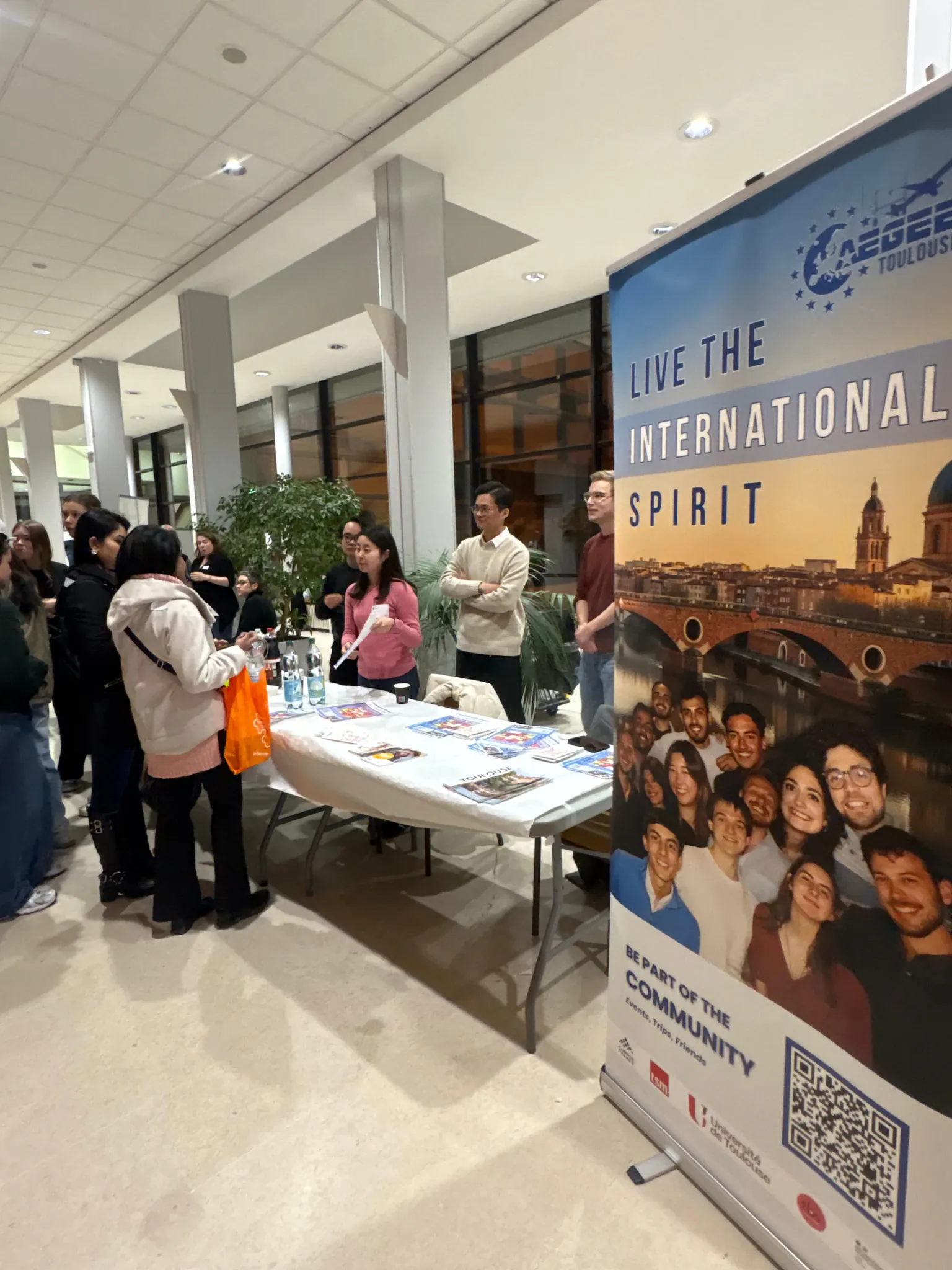A member talking with a small group of students gathered around an information table