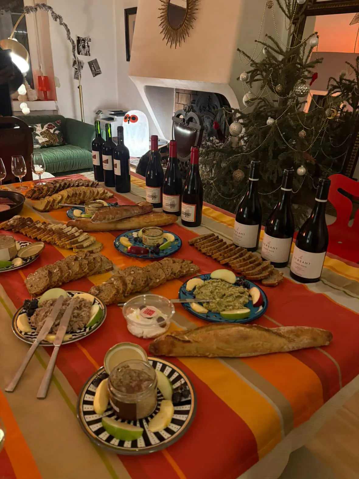 A table spread with wine bottles, sliced bread, pâté and charcuterie plates