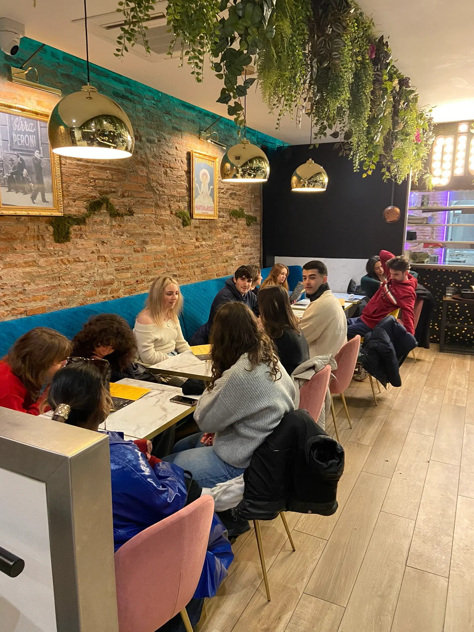 A group seated together at tables in a bar with plants, at the end of a walking tour