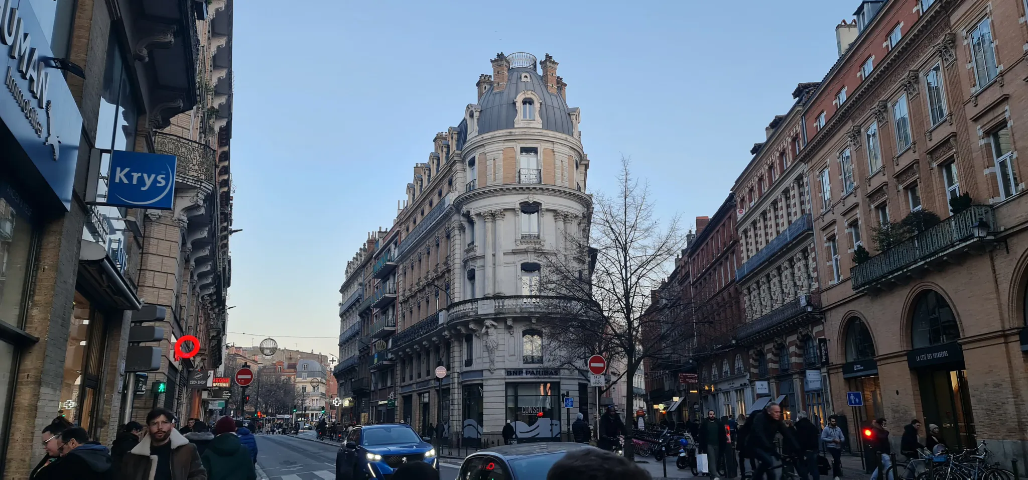 A Toulouse street corner with pedestrians, cyclists, and traffic