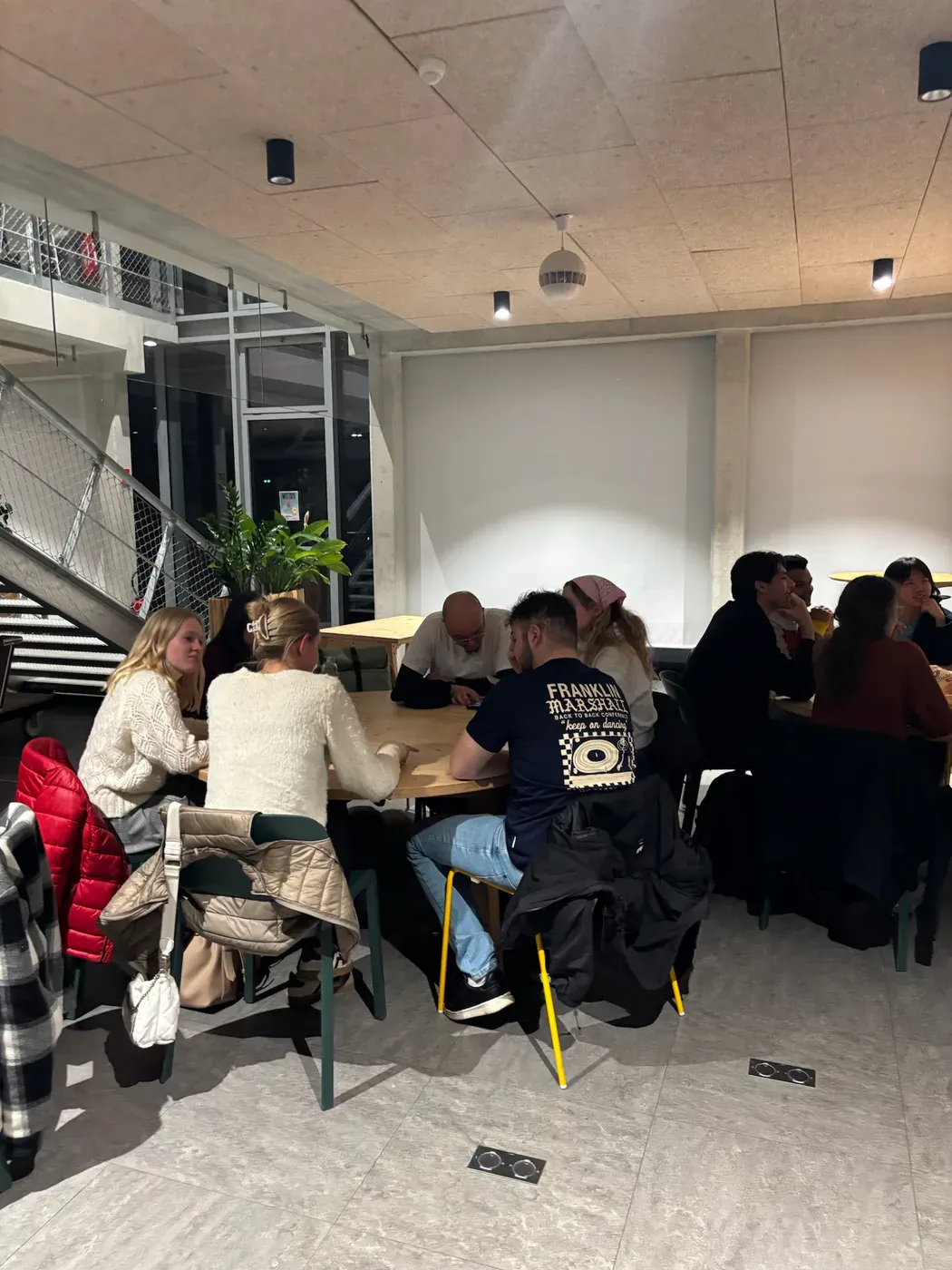 A small group of students in conversation around a round wooden table during a language workshop
